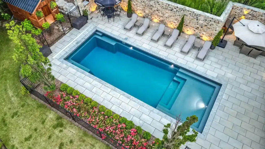 Modern backyard pool with square spa and landscaped garden