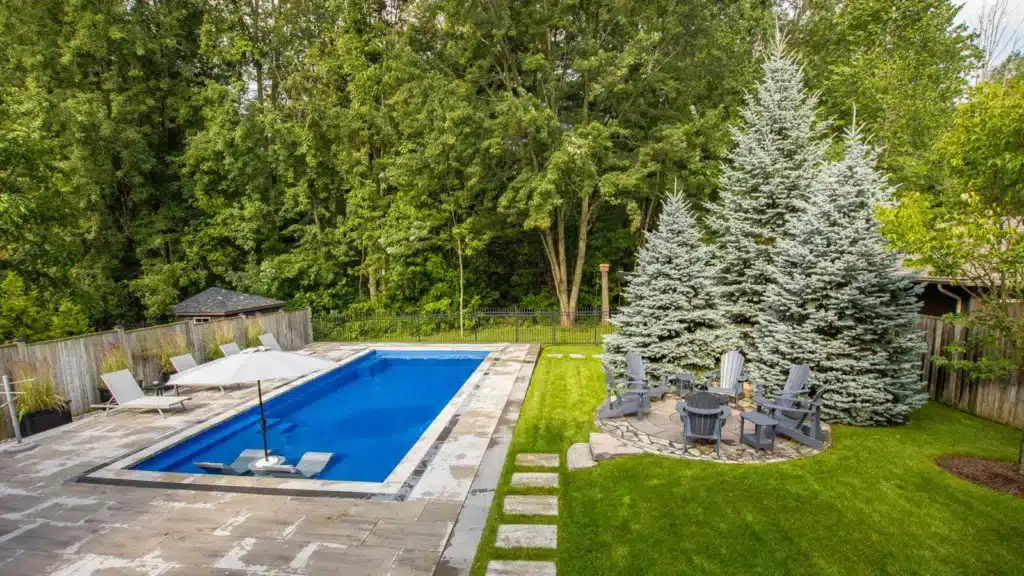 Compact rectangular pool in a private courtyard with patio furniture and wooden privacy fencing