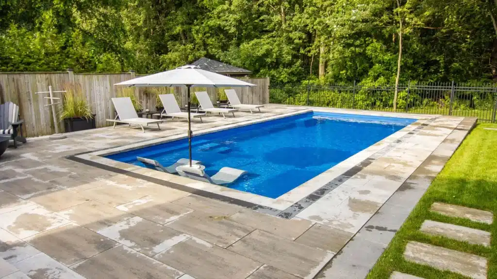 Compact rectangular pool in a private courtyard with patio furniture and wooden privacy fencing